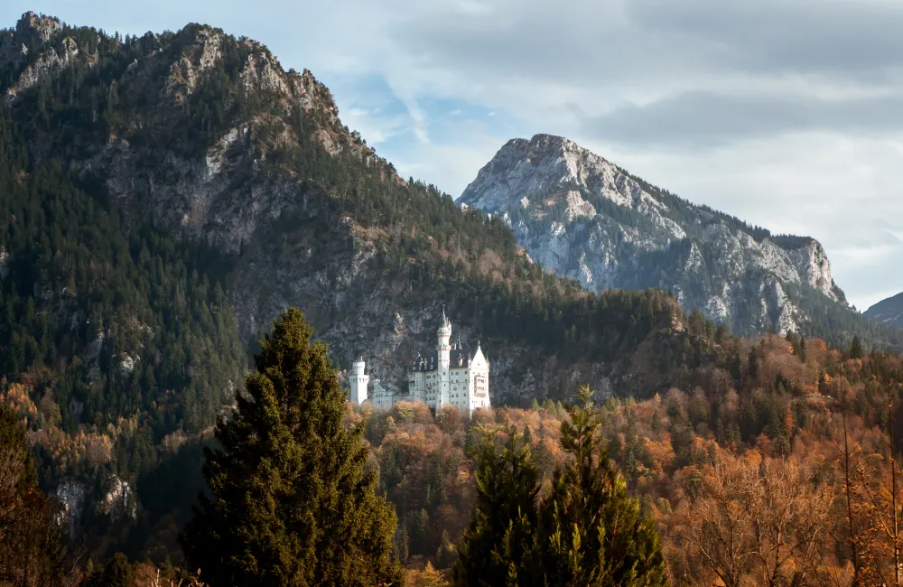 Schloss Neuschwanstein hinter einem bewaldeten Berg